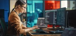 Young,Caucasian,Woman,Programming,On,Desktop,Computer,With,Two,Monitors